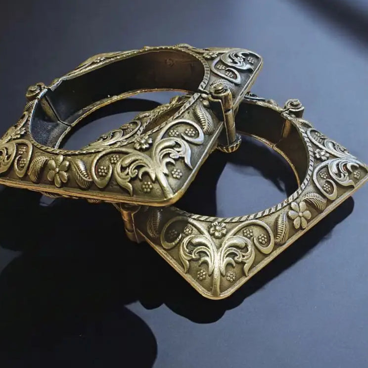 Decorative metal buckle with intricate designs on a dark background