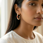 Woman wearing a pair of earrings with a neutral background