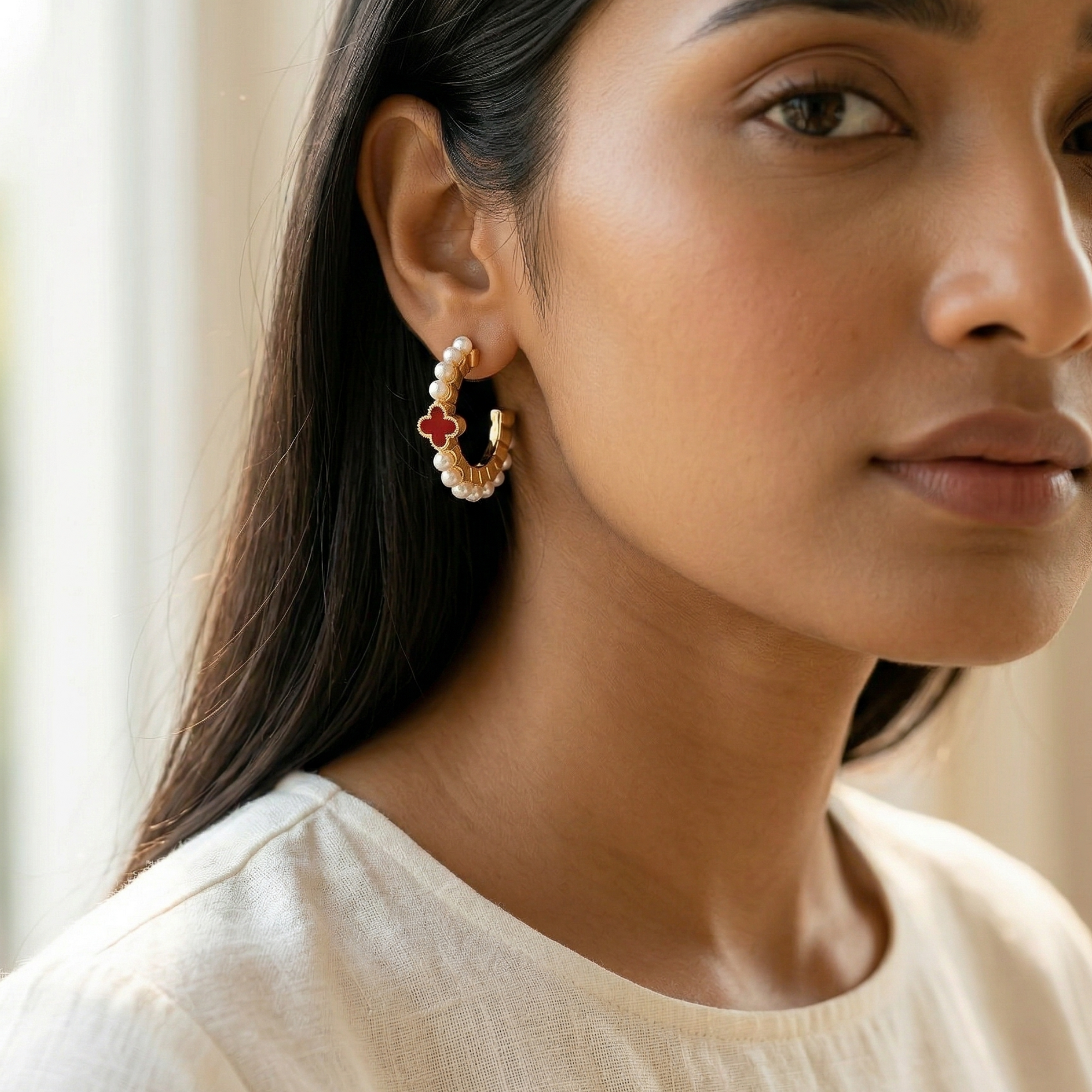Woman wearing a pair of earrings with a neutral background