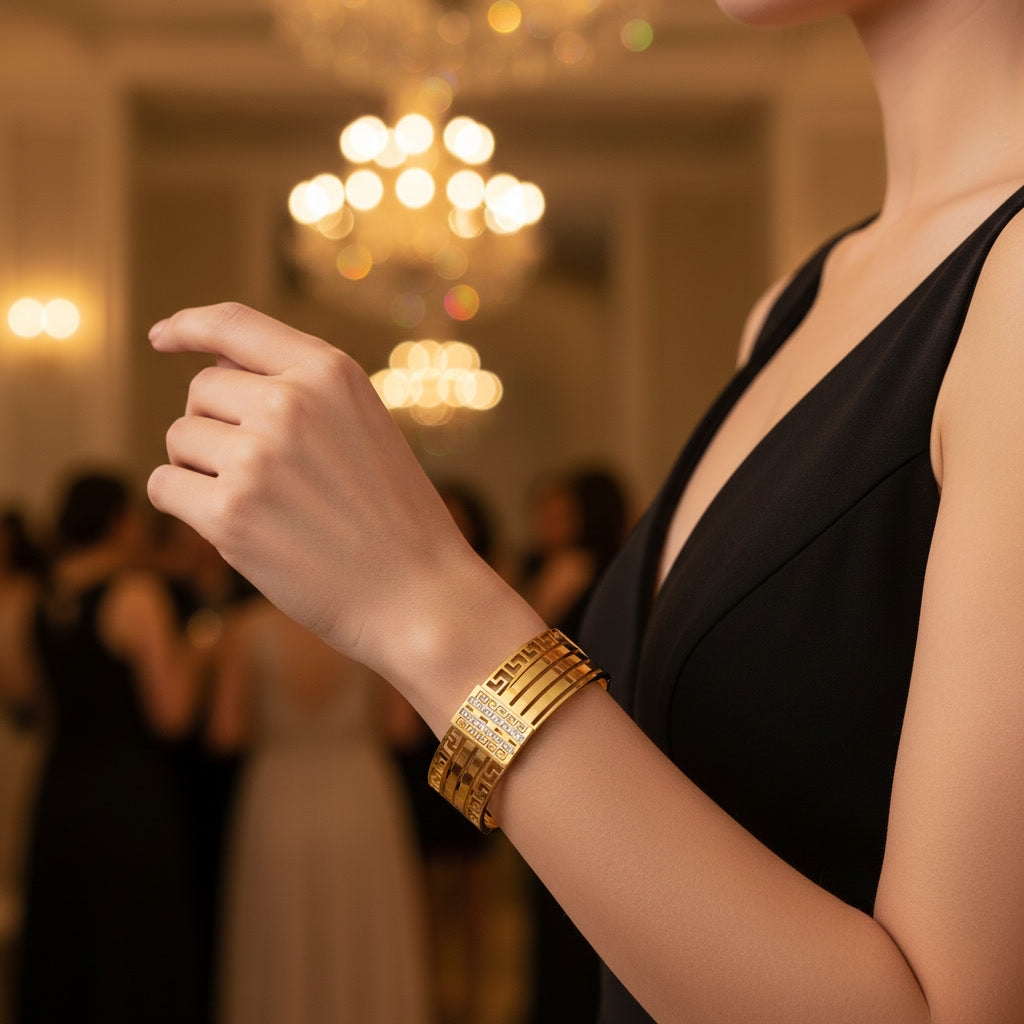 Person wearing a gold bracelet in an elegant indoor setting with chandeliers.