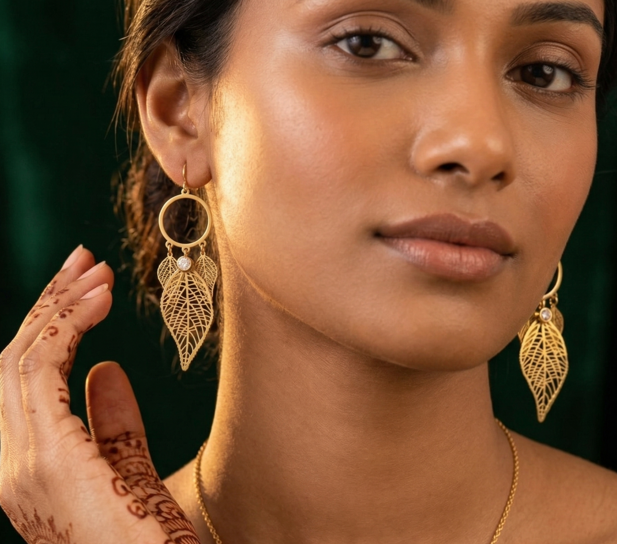 Woman wearing gold earrings with a green background