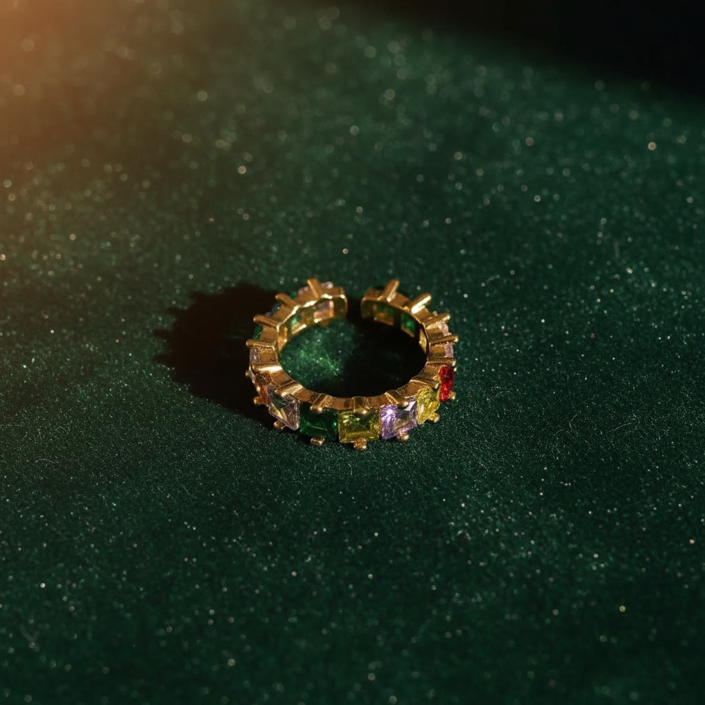 Gold ring with multicolored gemstones on a dark green textured background