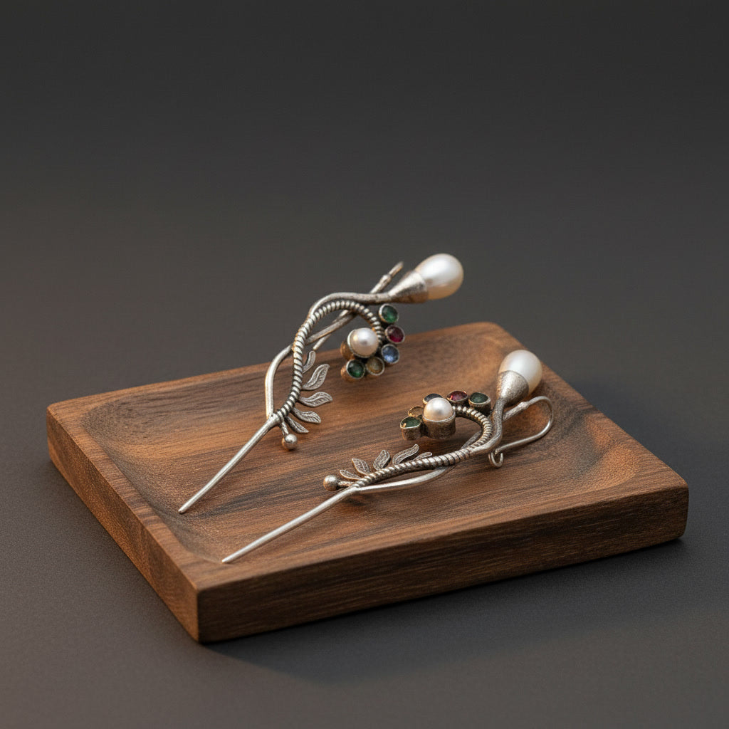 Pair of silver earrings with gemstones on a wooden stand against a dark background
