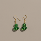 A pair of gold-tone dangle earrings with three faceted green crystal beads hanging from each hook, displayed on a neutral beige background.