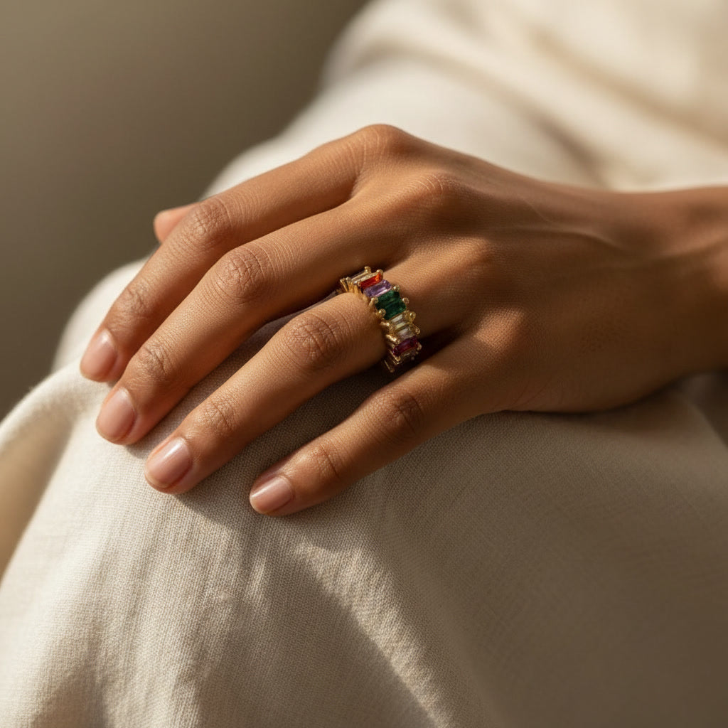 Hand wearing a colorful ring on a neutral background