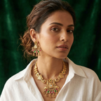 yugavi Mayuri antique gold peacock necklace and earring set flat lay — short haar with gold dori closure, double peacock pendant with ruby and emerald teardrop fringe, matching fan-shaped earrings — House of Yugavi
